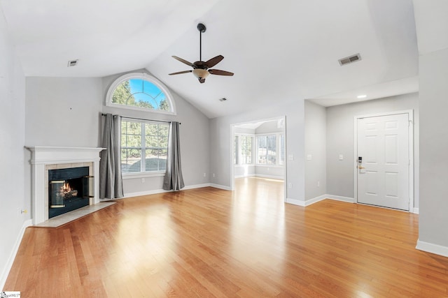 unfurnished living room featuring a tile fireplace, light wood-type flooring, vaulted ceiling, and ceiling fan