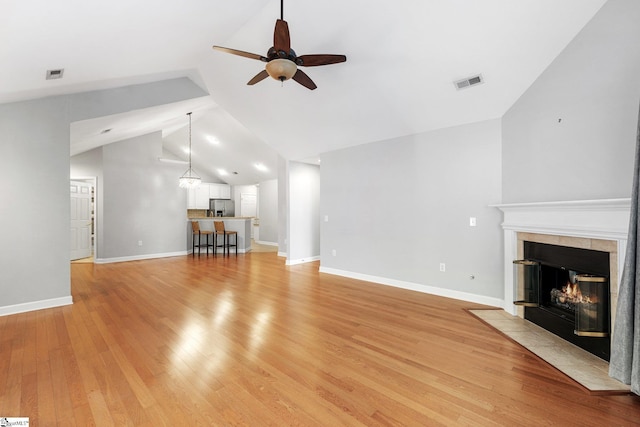 unfurnished living room featuring a tile fireplace, light hardwood / wood-style floors, ceiling fan, and lofted ceiling