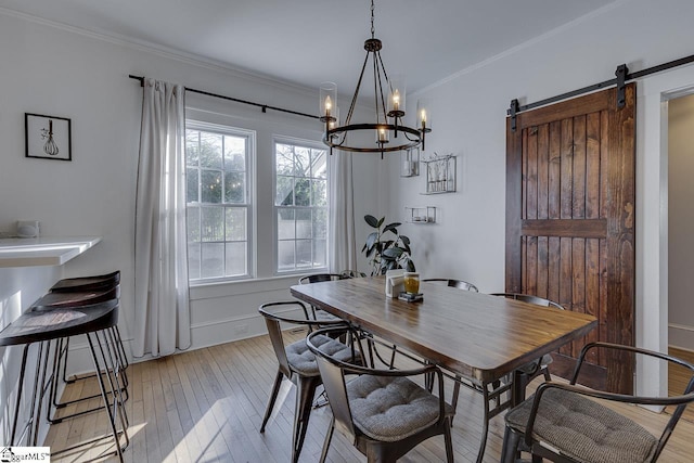 dining room with a chandelier, a barn door, crown molding, and light hardwood / wood-style flooring