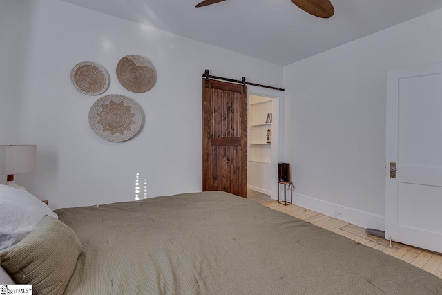 bedroom featuring ceiling fan, a barn door, and light hardwood / wood-style floors