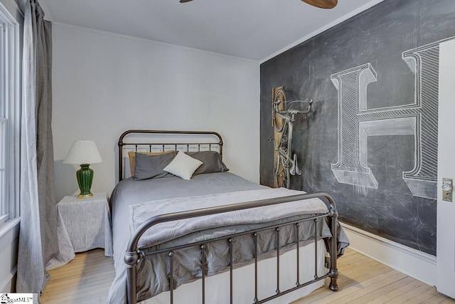 bedroom with light wood-type flooring, ceiling fan, and ornamental molding