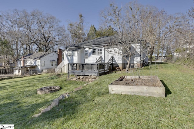 rear view of property with a fire pit, a wooden deck, and a lawn