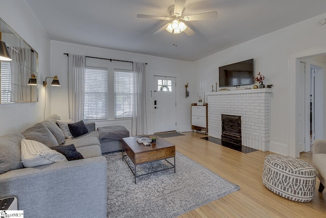 living room with ceiling fan, a fireplace, and wood-type flooring