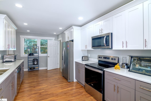 kitchen with white cabinets, gray cabinets, light hardwood / wood-style floors, and stainless steel appliances