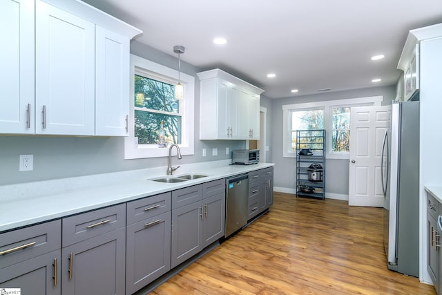 kitchen with sink, white cabinets, hanging light fixtures, and appliances with stainless steel finishes