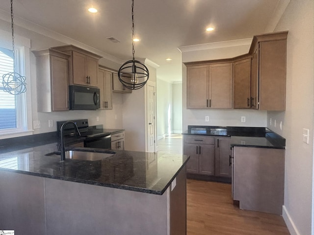 kitchen featuring hardwood / wood-style floors, black appliances, sink, hanging light fixtures, and dark stone countertops