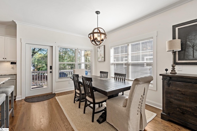 dining area with hardwood / wood-style flooring, a notable chandelier, and ornamental molding