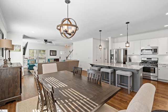 dining space featuring ceiling fan with notable chandelier, dark hardwood / wood-style floors, and ornamental molding