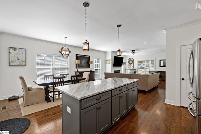 kitchen featuring stainless steel fridge, light stone counters, gray cabinetry, ceiling fan, and hanging light fixtures