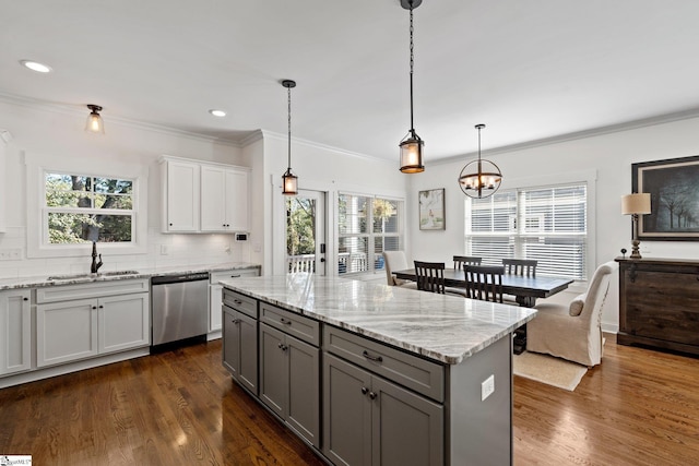 kitchen with hanging light fixtures, backsplash, sink, and stainless steel dishwasher