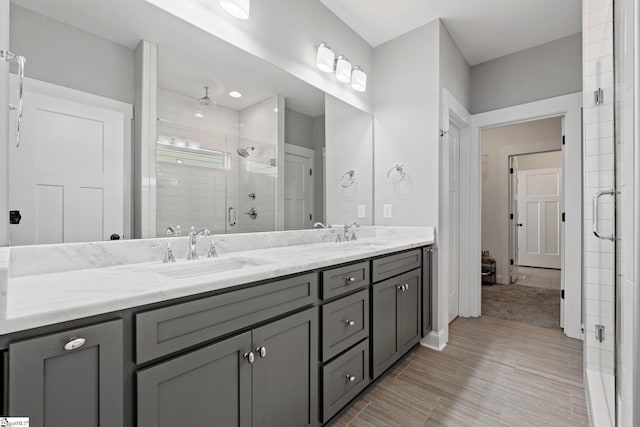 bathroom featuring a shower with door and vanity