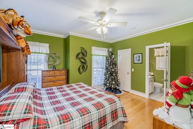 bedroom featuring ceiling fan, light hardwood / wood-style floors, ornamental molding, and ensuite bathroom