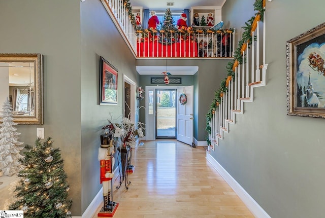 foyer entrance with visible vents, a high ceiling, wood finished floors, baseboards, and stairs