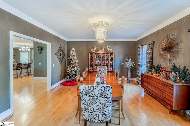 dining space featuring an inviting chandelier, light wood finished floors, and crown molding