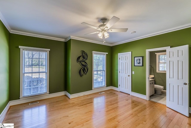 unfurnished room with ornamental molding, light wood-style flooring, visible vents, and baseboards