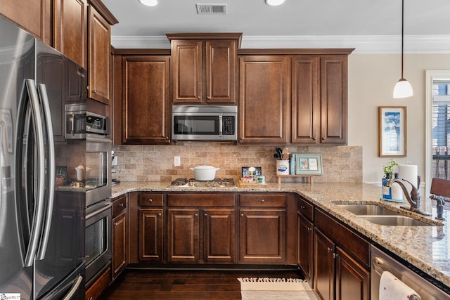 kitchen with hanging light fixtures, crown molding, sink, light stone countertops, and appliances with stainless steel finishes