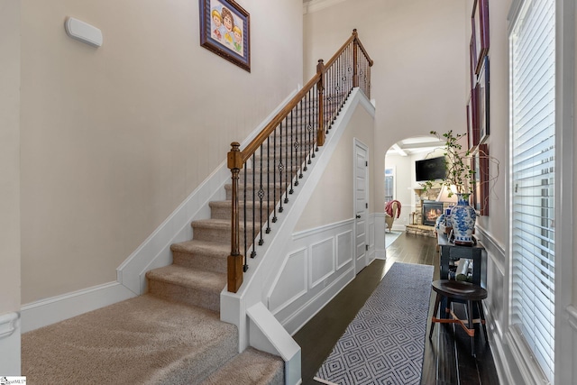 stairway with hardwood / wood-style floors and a stone fireplace