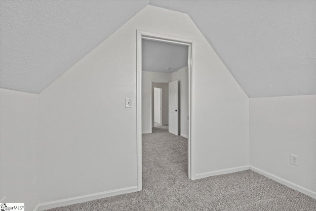 bonus room featuring light colored carpet, lofted ceiling, and a textured ceiling