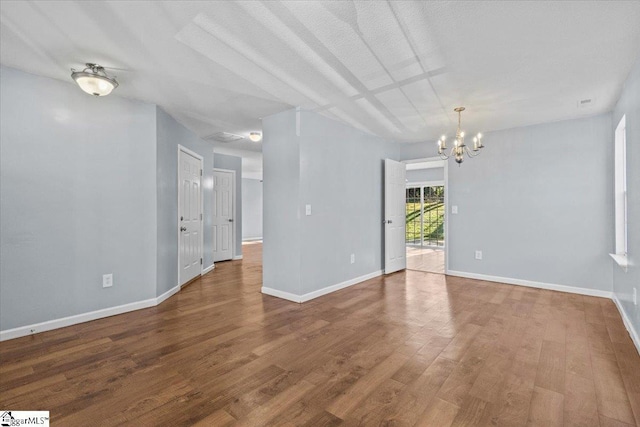 unfurnished room featuring a textured ceiling, hardwood / wood-style flooring, and an inviting chandelier