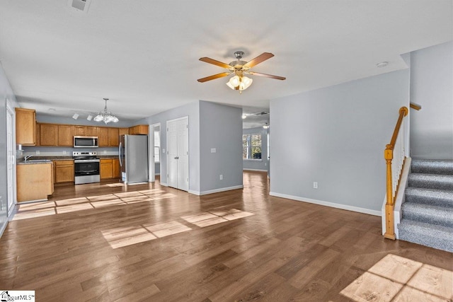 unfurnished living room featuring ceiling fan with notable chandelier, light hardwood / wood-style floors, and sink