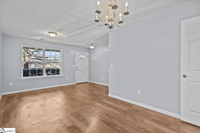 spare room featuring wood-type flooring, a textured ceiling, and a notable chandelier