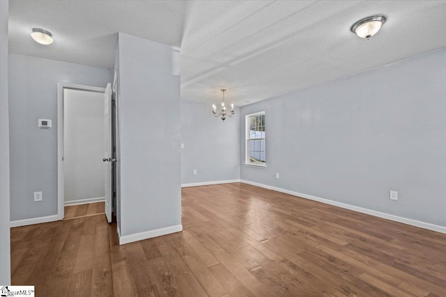 spare room featuring hardwood / wood-style floors, a textured ceiling, and an inviting chandelier