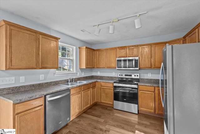 kitchen with track lighting, sink, light hardwood / wood-style flooring, a textured ceiling, and appliances with stainless steel finishes