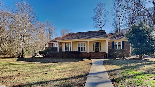 ranch-style house featuring covered porch and a front yard