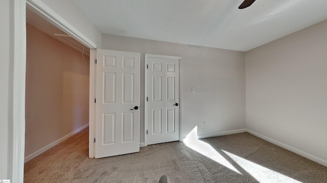 unfurnished bedroom with ceiling fan, light colored carpet, a textured ceiling, and a closet