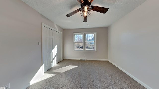 unfurnished bedroom featuring ceiling fan, a closet, light colored carpet, and a textured ceiling