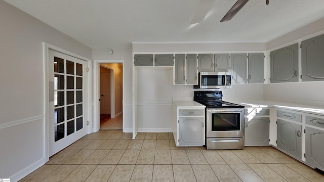 kitchen with ceiling fan, gray cabinets, light tile patterned floors, and appliances with stainless steel finishes