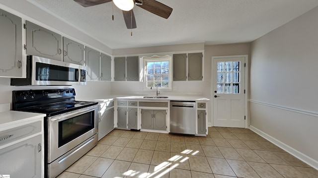 kitchen featuring sink, stainless steel appliances, a textured ceiling, gray cabinets, and light tile patterned floors