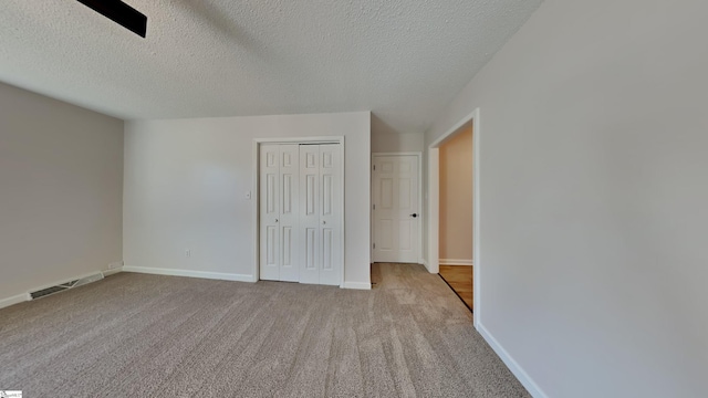 empty room with light carpet and a textured ceiling