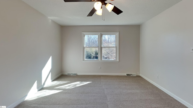 carpeted spare room with a textured ceiling and ceiling fan