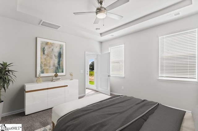 carpeted bedroom featuring ceiling fan and a tray ceiling