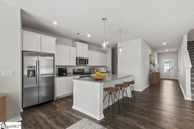 kitchen featuring white cabinetry, an island with sink, stainless steel appliances, and stone countertops