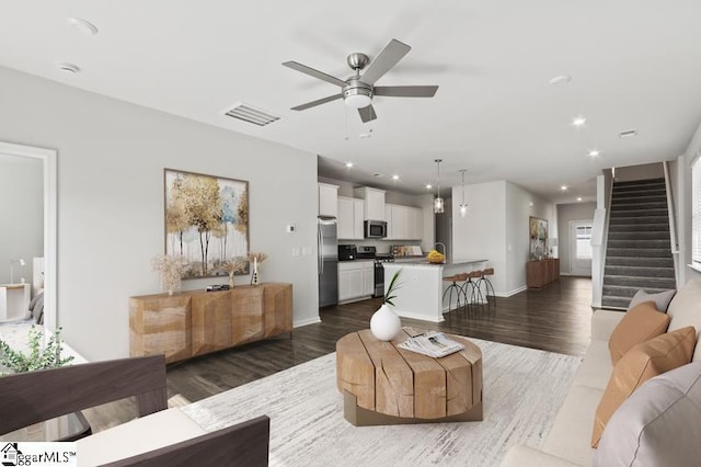 living room with ceiling fan and dark wood-type flooring