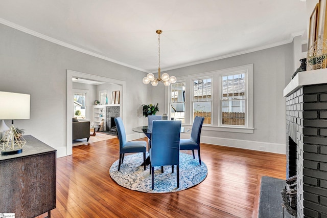 dining area featuring hardwood / wood-style floors, a brick fireplace, and crown molding