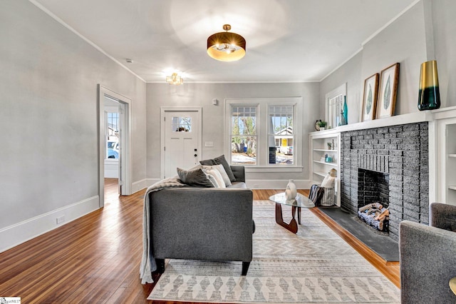 living room featuring wood-type flooring, ornamental molding, and a brick fireplace