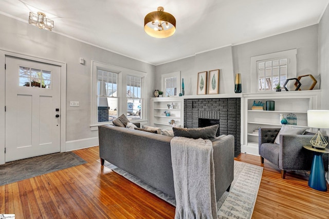 living room with crown molding, a fireplace, and wood-type flooring