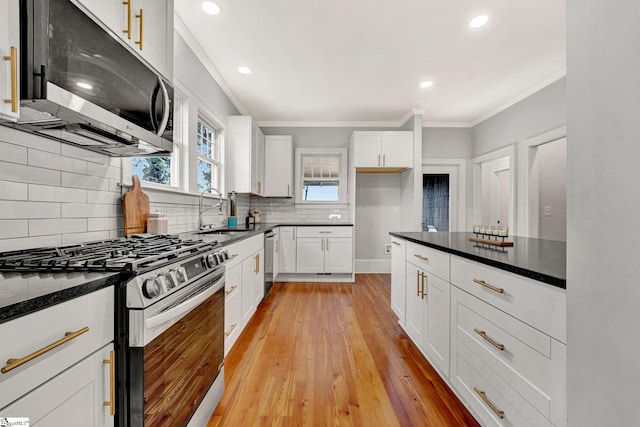 kitchen featuring dark stone counters, white cabinetry, sink, and stainless steel appliances