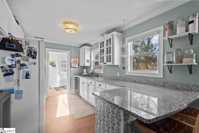 kitchen with white refrigerator, white cabinetry, and light stone counters