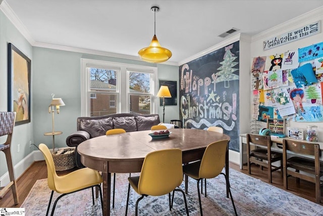 dining area with hardwood / wood-style flooring and ornamental molding