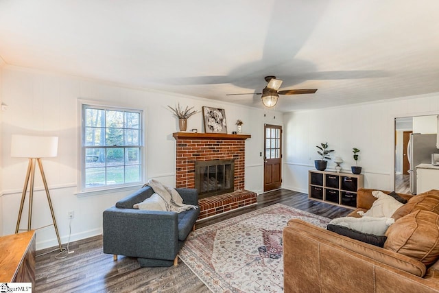 living room featuring dark hardwood / wood-style floors, ceiling fan, crown molding, and a fireplace