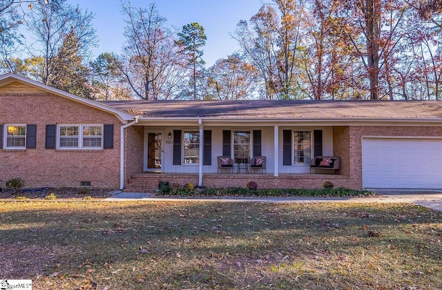 ranch-style home featuring covered porch, a front yard, and a garage