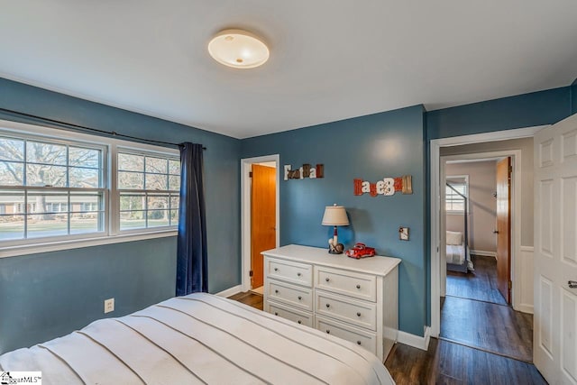 bedroom with multiple windows and dark hardwood / wood-style flooring