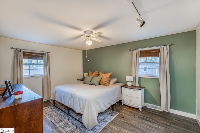 bedroom featuring ceiling fan, rail lighting, and dark hardwood / wood-style floors