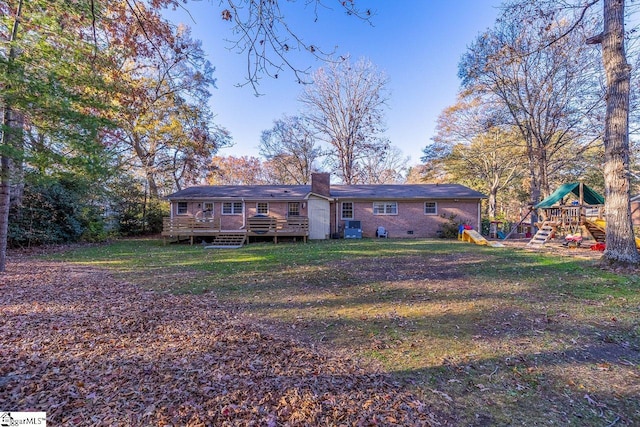 rear view of house featuring a playground, a yard, and a deck