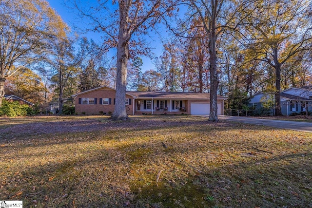 ranch-style home featuring covered porch, a front yard, and a garage