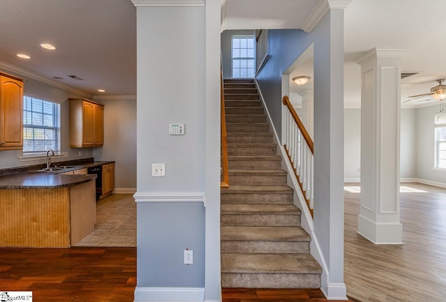 stairway featuring a wealth of natural light, sink, crown molding, and hardwood / wood-style flooring